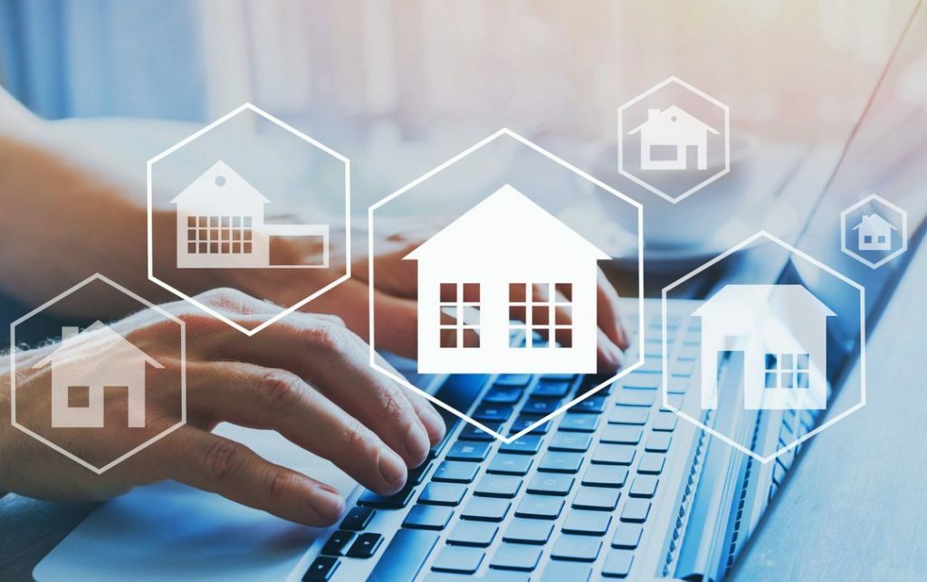 Hände auf Tastatur mit Haus Icons, veranschaulicht die Digitaliserung der Immobilienbranche