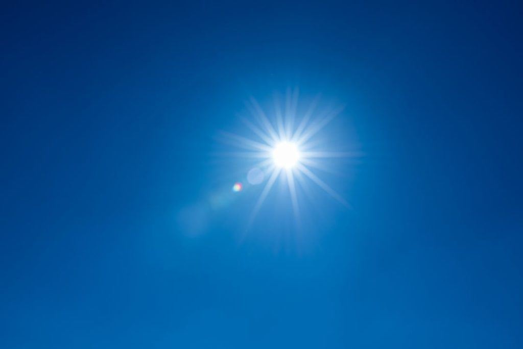 Sonne vor blauem Himmel, verbildlicht die Photovoltaik Rendite 2023