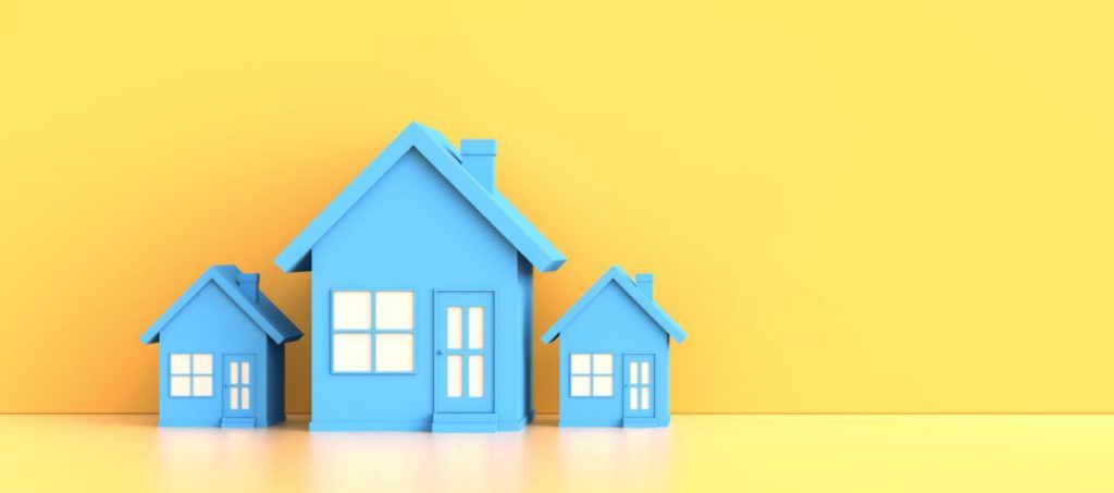 Drei blaue Modellhäuser vor gelbem Hintergrund- Symbol für die besten Immobilienportale im Internet